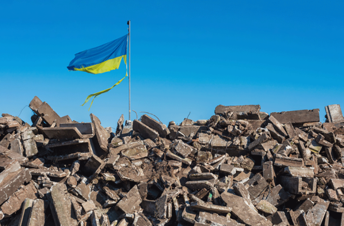 ukraine flag above rubble