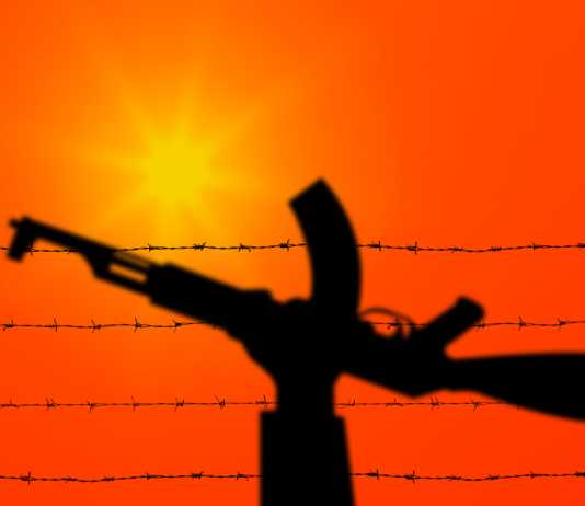 How the ‘Laws of War’ Apply to the Conflict Between Israel and Hamas Palestine and Israel conflict. Hand holding gun over barbed wire. Terrorist organizations hezbollah and hamas