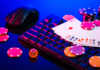 How Live Dealer Games Are Changing the Online Casino Experience A vibrant arrangement of poker chips and playing cards on a gaming keyboard with a mouse at an online casino setup during the evening