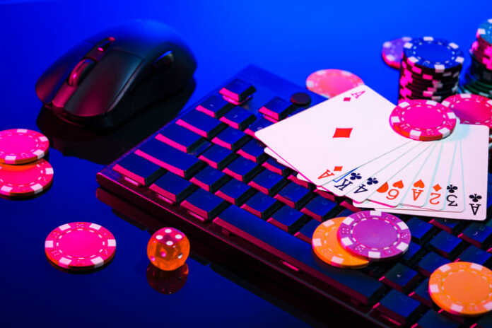 A vibrant arrangement of poker chips and playing cards on a gaming keyboard with a mouse at an online casino setup during the evening