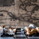Two king fighting on chess board with earth map background. Business strategy and competition concept.